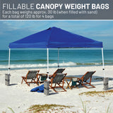 Blue canopy tent on a sandy beach with chairs and tables, featuring fillable canopy weight bags.